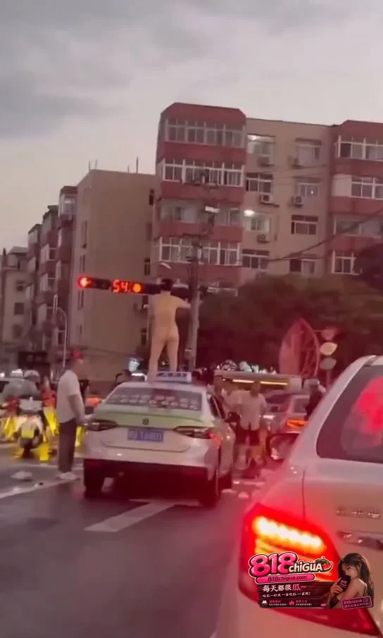 青岛街头惊现裸女车顶热舞！女子当街脱光衣服扭腰摆臀，出租车顶成舞台，路口车辆行人全看傻，场面混乱又荒诞！